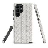 A stylish, impact-resistant phone case with a textured white braided design, covering the back of a smartphone. The dual-layer design features cutouts for the camera and buttons, and "Cozy Knit Bliss for Samsung" by Statement Cases is embossed at the bottom.