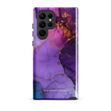 The Golden Orchid Marble for Samsung by Statement Cases is a smartphone adorned with a vibrant, abstract phone case showcasing a mix of purple, pink, and gold colors. Crafted from impact-resistant materials, it features a camera module with four lenses and a flash. At the bottom of the shock-absorbing phone case, you’ll find the text "STATEMENT CASES" in white.