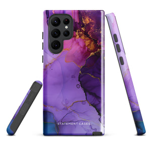 The Golden Orchid Marble for Samsung by Statement Cases is a smartphone adorned with a vibrant, abstract phone case showcasing a mix of purple, pink, and gold colors. Crafted from impact-resistant materials, it features a camera module with four lenses and a flash. At the bottom of the shock-absorbing phone case, you’ll find the text "STATEMENT CASES" in white.