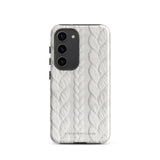 A stylish, impact-resistant phone case with a textured white braided design, covering the back of a smartphone. The dual-layer design features cutouts for the camera and buttons, and "Cozy Knit Bliss for Samsung" by Statement Cases is embossed at the bottom.