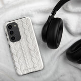 A stylish, impact-resistant phone case with a textured white braided design, covering the back of a smartphone. The dual-layer design features cutouts for the camera and buttons, and "Cozy Knit Bliss for Samsung" by Statement Cases is embossed at the bottom.
