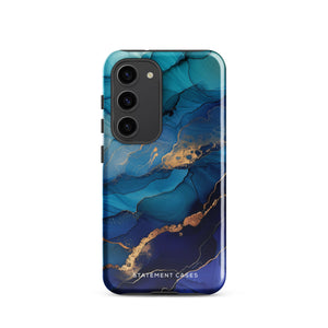 A Samsung smartphone adorned with the Midnight Wave Marble—a vibrant, blue and gold marble-patterned dual-layer phone case. Featuring multiple camera lenses at the top left corner, this impact-resistant case is elegantly labeled "Statement Cases" in white text at the bottom. The design showcases fluid, swirling layers with metallic accents.