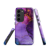 The Golden Orchid Marble for Samsung by Statement Cases is a smartphone adorned with a vibrant, abstract phone case showcasing a mix of purple, pink, and gold colors. Crafted from impact-resistant materials, it features a camera module with four lenses and a flash. At the bottom of the shock-absorbing phone case, you’ll find the text "STATEMENT CASES" in white.