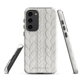 A stylish, impact-resistant phone case with a textured white braided design, covering the back of a smartphone. The dual-layer design features cutouts for the camera and buttons, and "Cozy Knit Bliss for Samsung" by Statement Cases is embossed at the bottom.