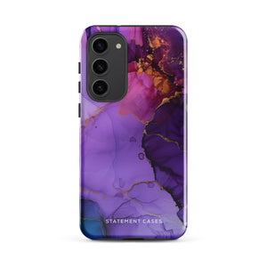 The Golden Orchid Marble for Samsung by Statement Cases is a smartphone adorned with a vibrant, abstract phone case showcasing a mix of purple, pink, and gold colors. Crafted from impact-resistant materials, it features a camera module with four lenses and a flash. At the bottom of the shock-absorbing phone case, you’ll find the text "STATEMENT CASES" in white.