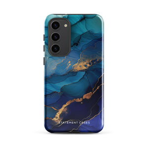 A Samsung smartphone adorned with the Midnight Wave Marble—a vibrant, blue and gold marble-patterned dual-layer phone case. Featuring multiple camera lenses at the top left corner, this impact-resistant case is elegantly labeled "Statement Cases" in white text at the bottom. The design showcases fluid, swirling layers with metallic accents.