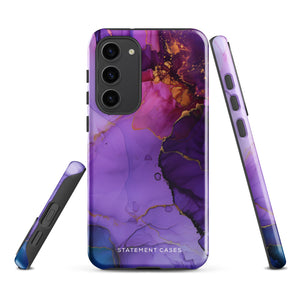 The Golden Orchid Marble for Samsung by Statement Cases is a smartphone adorned with a vibrant, abstract phone case showcasing a mix of purple, pink, and gold colors. Crafted from impact-resistant materials, it features a camera module with four lenses and a flash. At the bottom of the shock-absorbing phone case, you’ll find the text "STATEMENT CASES" in white.