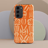 This stylish smartphone accessory, the Savannah Ardiente for Samsung by Statement Cases, features a shock-absorbing, colorful patterned case adorned with abstract flower designs in beige on an orange background. This impact-resistant phone case wraps around the back of your device, providing robust protection for its multiple camera lenses in the corner.