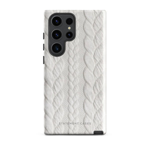 A stylish, impact-resistant phone case with a textured white braided design, covering the back of a smartphone. The dual-layer design features cutouts for the camera and buttons, and "Cozy Knit Bliss for Samsung" by Statement Cases is embossed at the bottom.