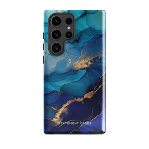 A Samsung smartphone adorned with the Midnight Wave Marble—a vibrant, blue and gold marble-patterned dual-layer phone case. Featuring multiple camera lenses at the top left corner, this impact-resistant case is elegantly labeled "Statement Cases" in white text at the bottom. The design showcases fluid, swirling layers with metallic accents.