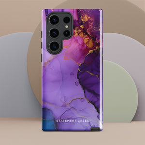 The Golden Orchid Marble for Samsung by Statement Cases is a smartphone adorned with a vibrant, abstract phone case showcasing a mix of purple, pink, and gold colors. Crafted from impact-resistant materials, it features a camera module with four lenses and a flash. At the bottom of the shock-absorbing phone case, you’ll find the text "STATEMENT CASES" in white.