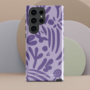 Introducing the Luna Morada for Samsung, a striking smartphone case from Statement Cases. This decorative purple cover boasts abstract floral and organic patterns in darker hues and is designed to absorb shocks. The impact-resistant case features a camera cutout that accommodates five lenses, with the brand name "STATEMENT CASES" elegantly printed at the bottom center.