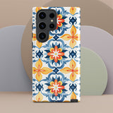 The Mediterranean Bloom for Samsung by Statement Cases features intricate, colorful floral patterns in blue, orange, and yellow. The design covers the entire back of the case, surrounding the camera cutout. Shock-absorbing and impact-resistant, it ensures protection while the brand "Statement Cases" is subtly printed near the bottom.