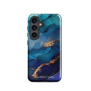 A Samsung smartphone adorned with the Midnight Wave Marble—a vibrant, blue and gold marble-patterned dual-layer phone case. Featuring multiple camera lenses at the top left corner, this impact-resistant case is elegantly labeled "Statement Cases" in white text at the bottom. The design showcases fluid, swirling layers with metallic accents.