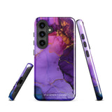 The Golden Orchid Marble for Samsung by Statement Cases is a smartphone adorned with a vibrant, abstract phone case showcasing a mix of purple, pink, and gold colors. Crafted from impact-resistant materials, it features a camera module with four lenses and a flash. At the bottom of the shock-absorbing phone case, you’ll find the text "STATEMENT CASES" in white.