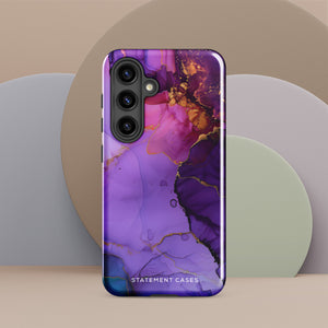 The Golden Orchid Marble for Samsung by Statement Cases is a smartphone adorned with a vibrant, abstract phone case showcasing a mix of purple, pink, and gold colors. Crafted from impact-resistant materials, it features a camera module with four lenses and a flash. At the bottom of the shock-absorbing phone case, you’ll find the text "STATEMENT CASES" in white.