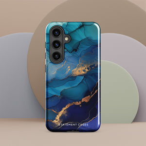 A Samsung smartphone adorned with the Midnight Wave Marble—a vibrant, blue and gold marble-patterned dual-layer phone case. Featuring multiple camera lenses at the top left corner, this impact-resistant case is elegantly labeled "Statement Cases" in white text at the bottom. The design showcases fluid, swirling layers with metallic accents.