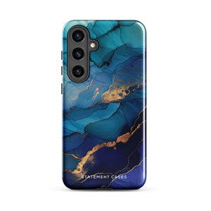 A Samsung smartphone adorned with the Midnight Wave Marble—a vibrant, blue and gold marble-patterned dual-layer phone case. Featuring multiple camera lenses at the top left corner, this impact-resistant case is elegantly labeled "Statement Cases" in white text at the bottom. The design showcases fluid, swirling layers with metallic accents.