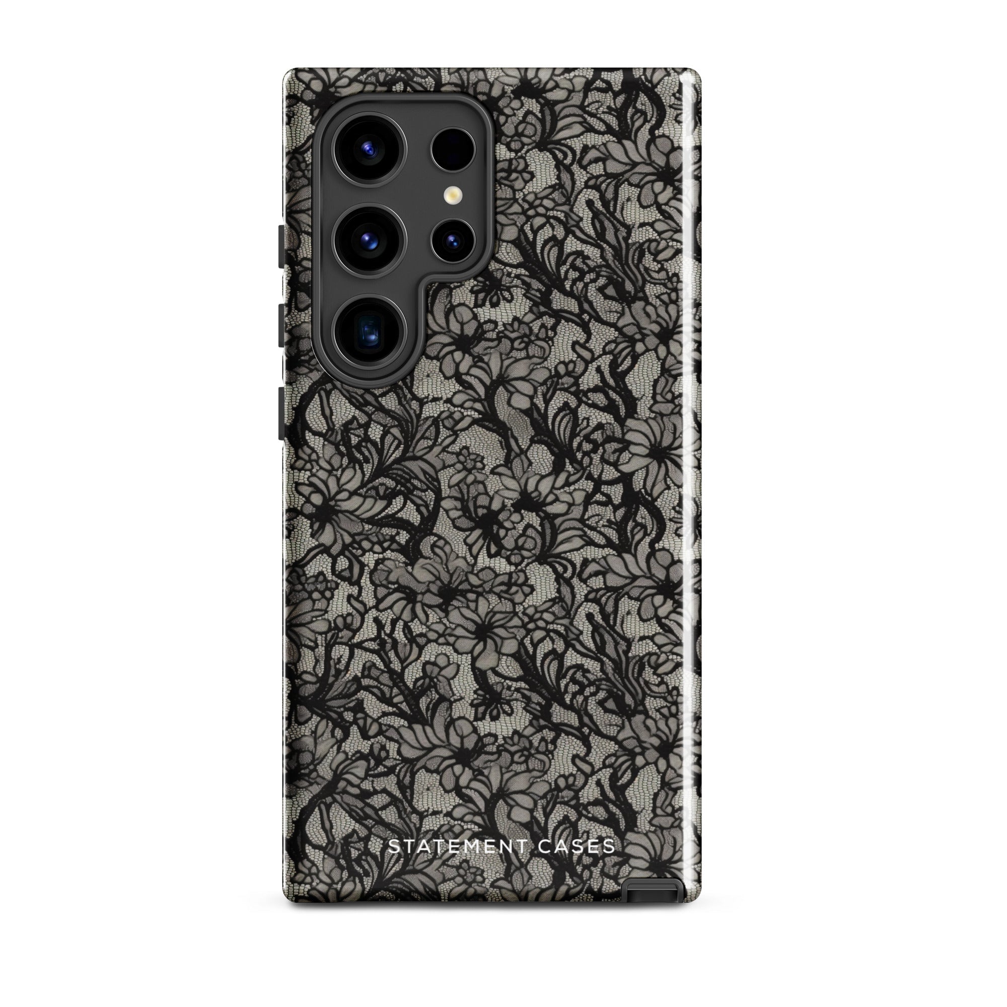 A phone case with a protective dual-layer design featuring an intricate black floral lace pattern. The Omerta Floral for Samsung has four camera cutouts and the brand name "Statement Cases" appears at the bottom center. Impact-resistant and chic, it stands against a plain white background.