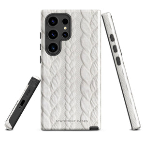 A stylish, impact-resistant phone case with a textured white braided design, covering the back of a smartphone. The dual-layer design features cutouts for the camera and buttons, and "Cozy Knit Bliss for Samsung" by Statement Cases is embossed at the bottom.