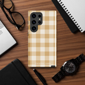 A beige and white checkered phone case is shown. Designed to fit a smartphone with a horizontal dual-camera setup, it features "STATEMENT CASES" printed at the bottom. This impact-resistant phone case offers both style and protection.Product Name: Gingham Grace for Samsung Brand Name: Statement Cases