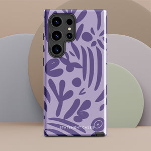 Introducing the Luna Morada for Samsung, a striking smartphone case from Statement Cases. This decorative purple cover boasts abstract floral and organic patterns in darker hues and is designed to absorb shocks. The impact-resistant case features a camera cutout that accommodates five lenses, with the brand name "STATEMENT CASES" elegantly printed at the bottom center.