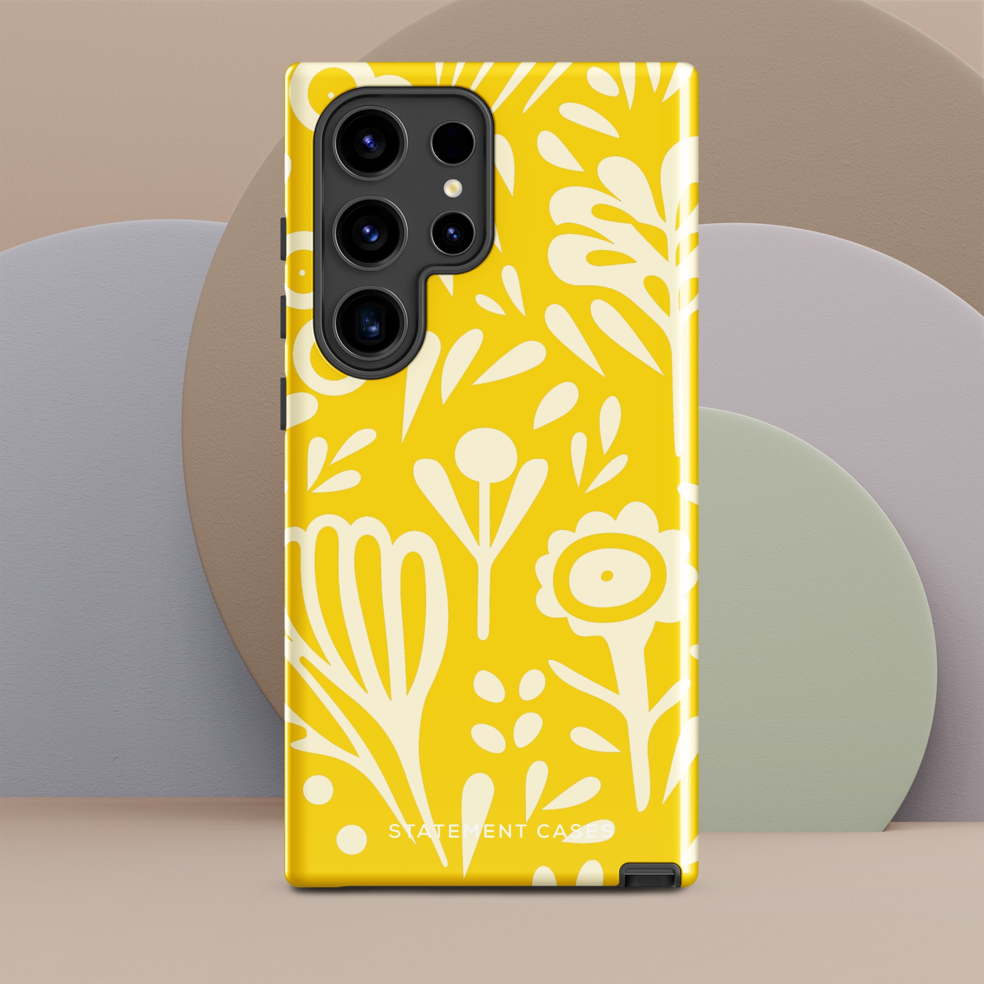 The Sol Dorado for Samsung by Statement Cases is a durable phone case featuring a bright yellow background adorned with an abstract white floral pattern, showcasing various flowers and leaves. Near the bottom edge, the text "STATEMENT CASE" highlights its dual-layer design for enhanced durability.